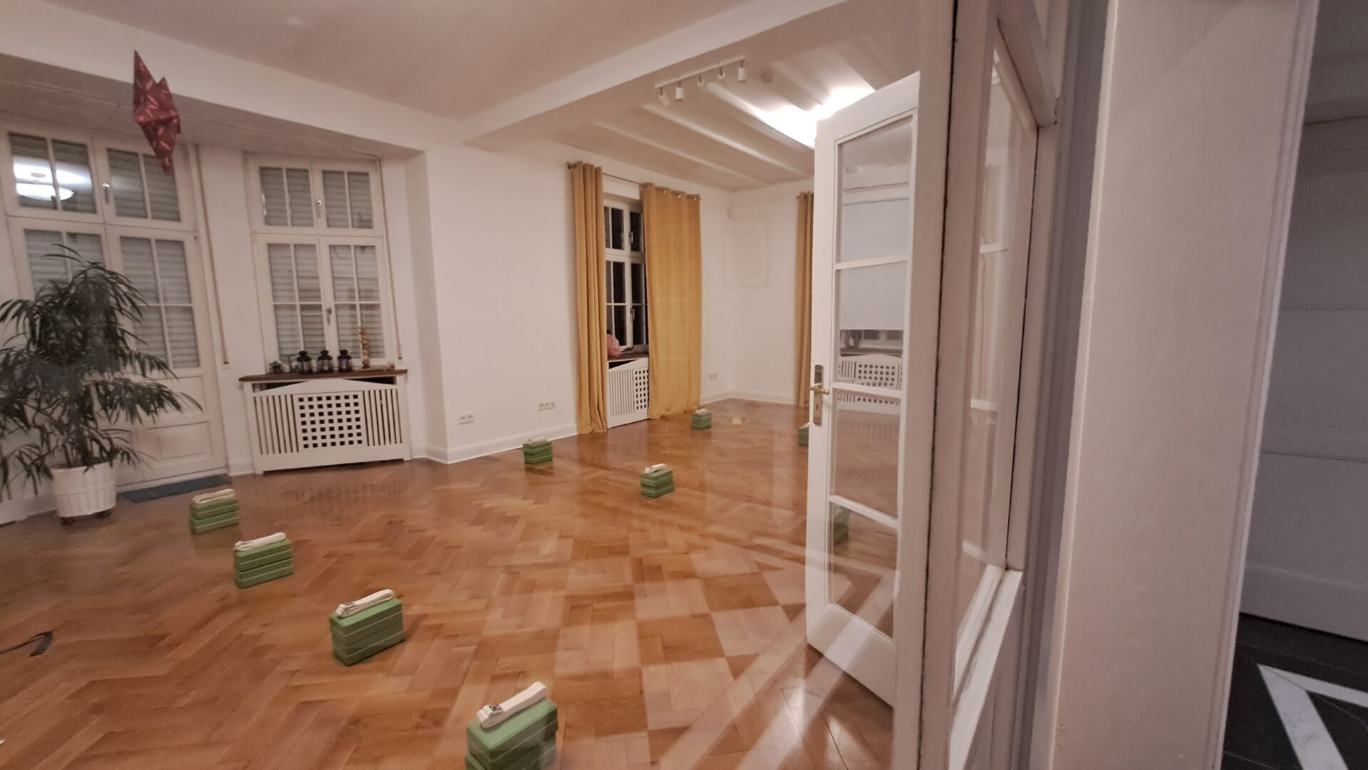 Leerer Yoga-Raum mit Holzfußboden und grünen Blöcken.